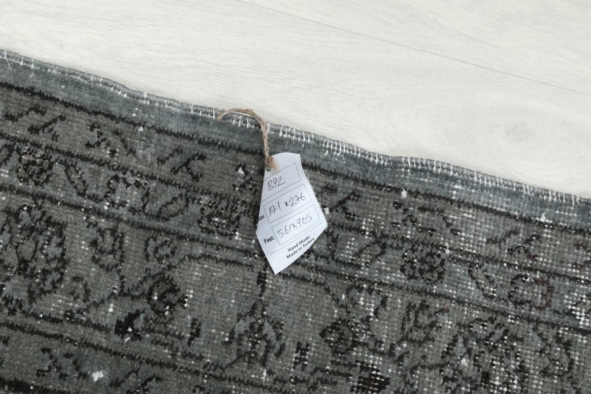 Rug tag attached to the corner of the vintage blue and gray hand-knotted rug