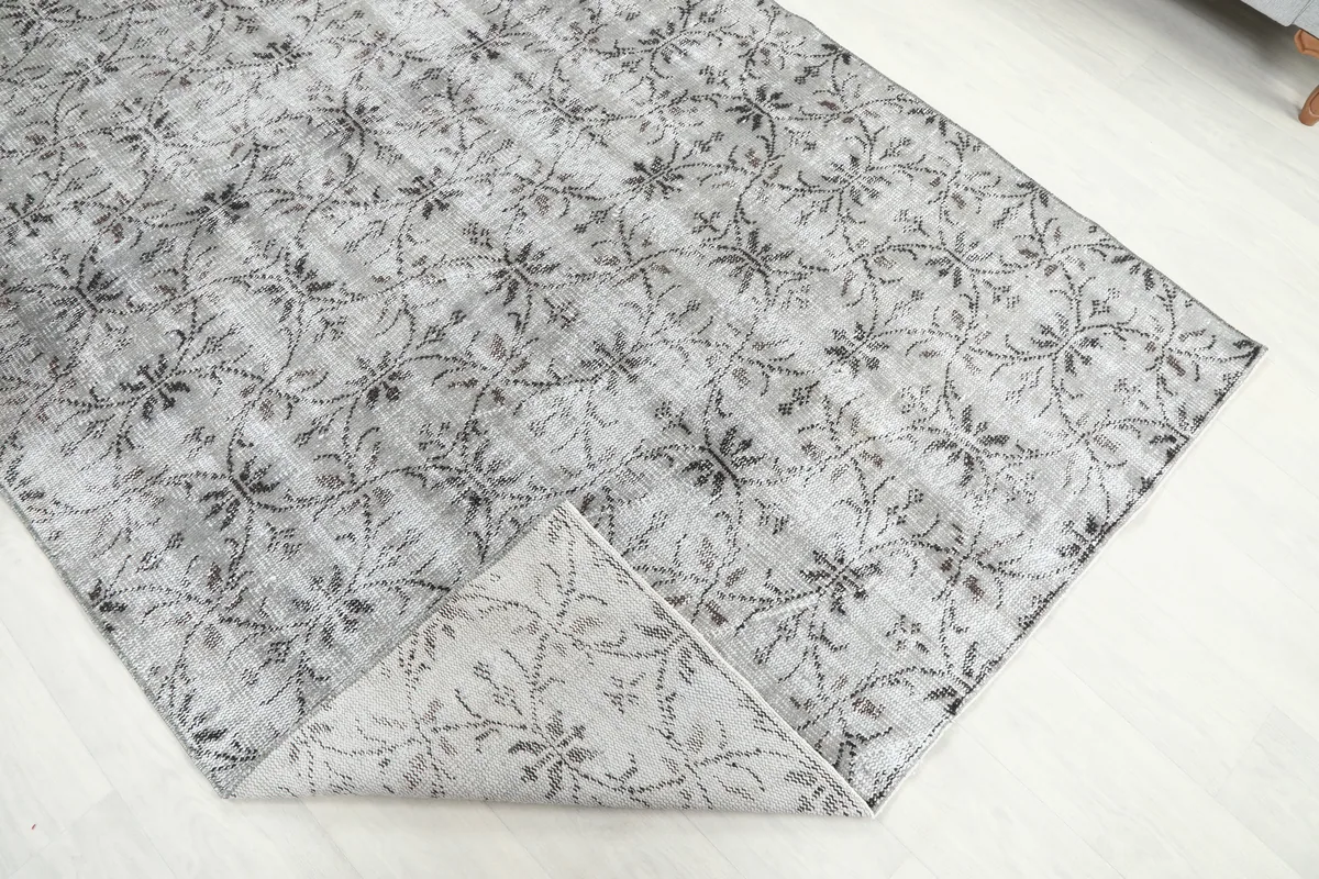Gray Floral Anatolian Rug folded back to reveal the back of the rug and the cotton foundation.