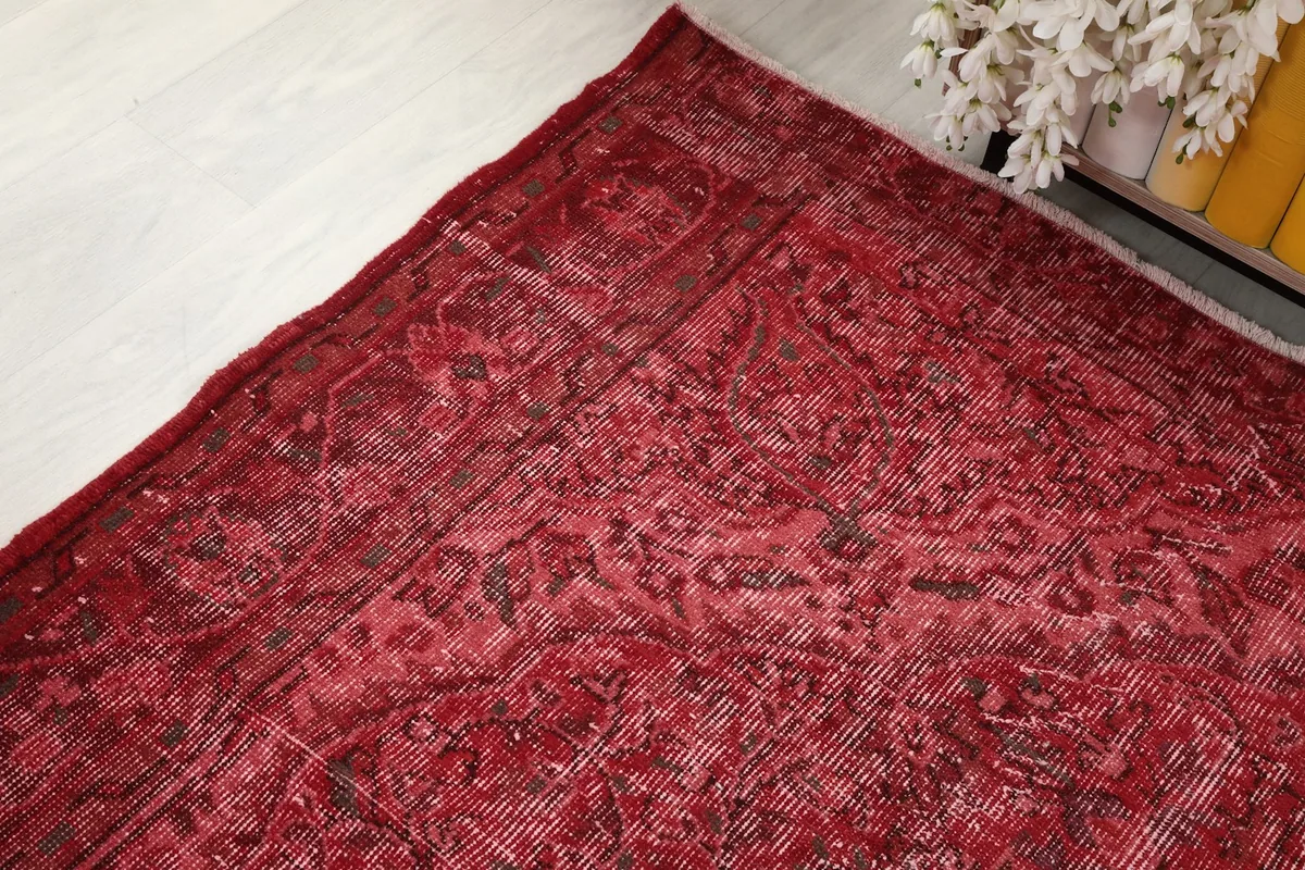 Another angle shot of the red vintage rug, emphasizing the overall color and pattern variation.