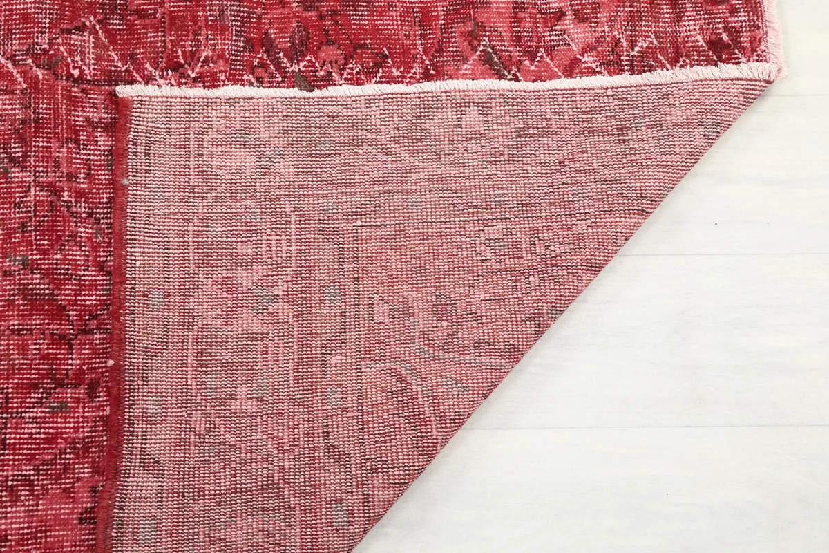 Underside of the red vintage rug, revealing the cotton foundation and hand-knotted construction.