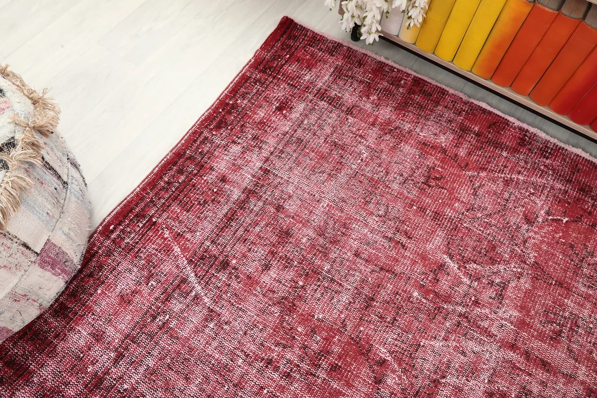 Corner view of the red distressed rug, showing its interaction with the surrounding floor