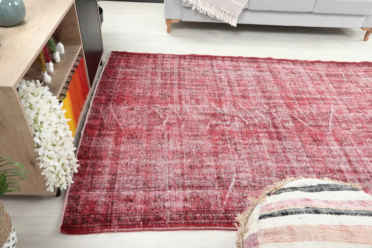 Full view of the red distressed rug in a room, showcasing its medium size and color