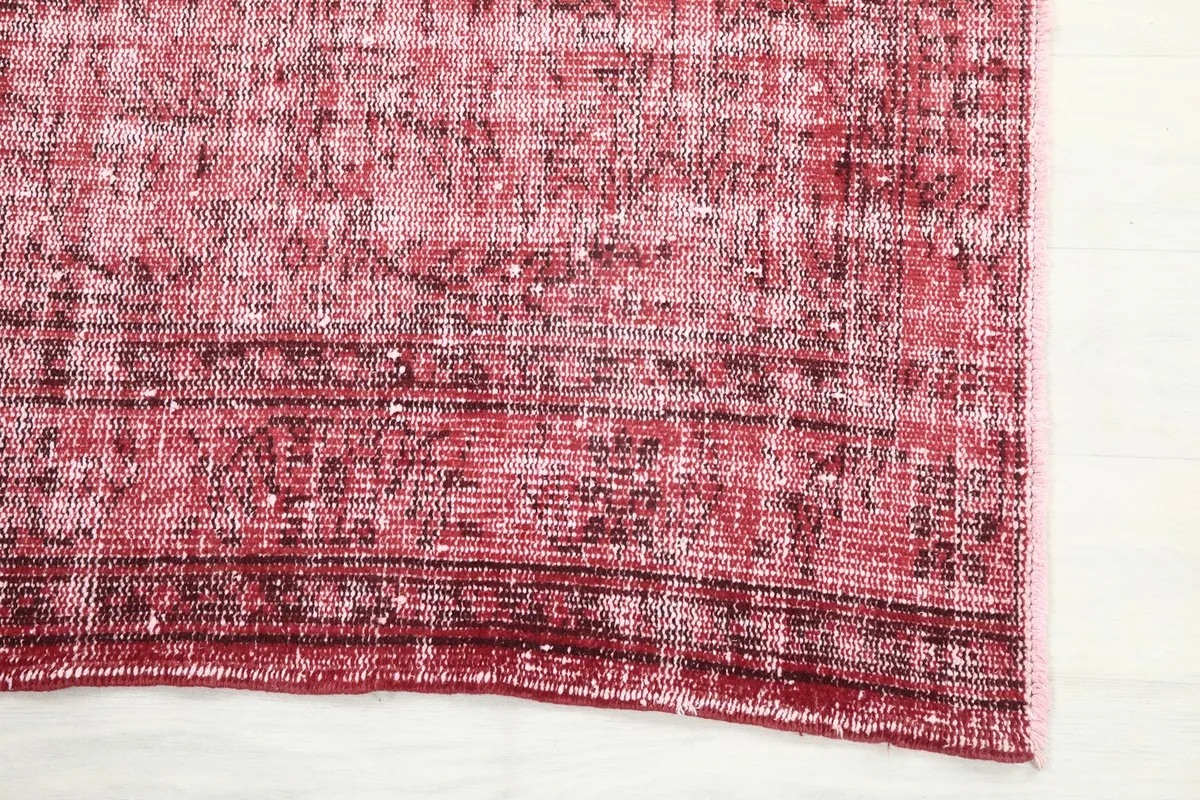 Detailed view of the rug's edge, highlighting the faded red and subtle patterns