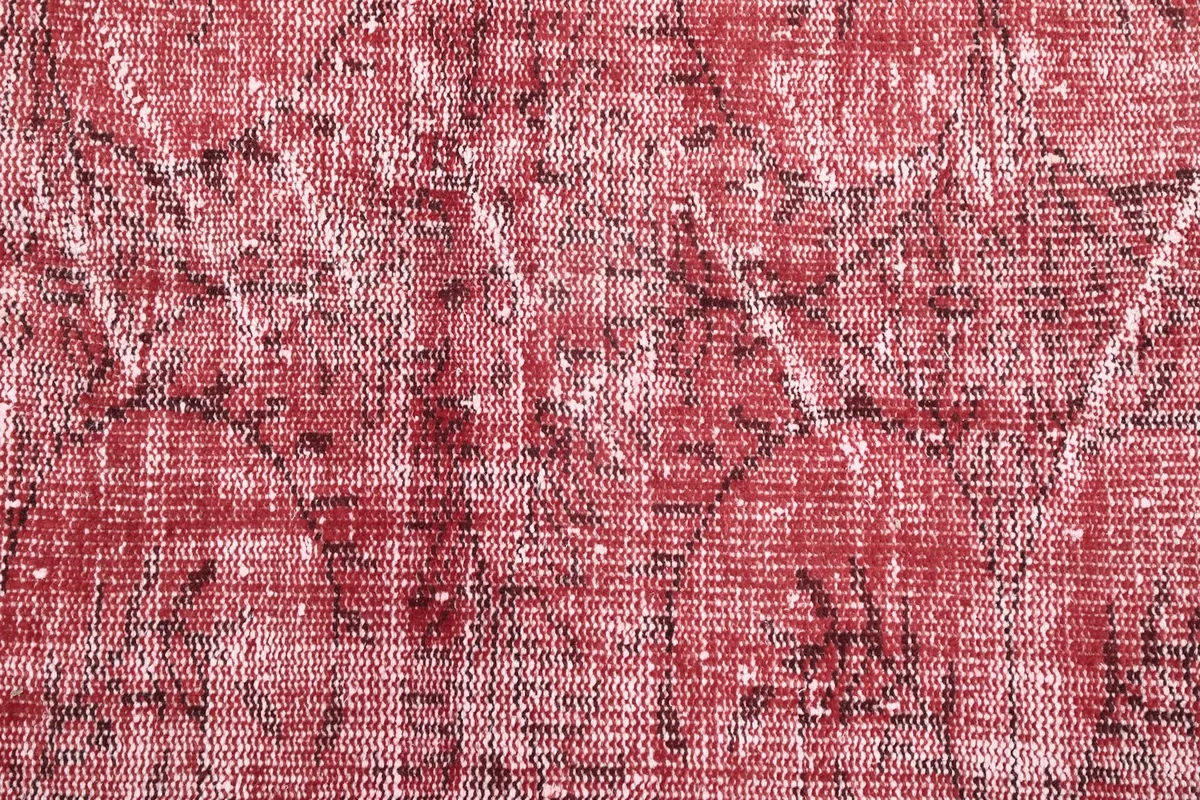 Macro detail of the hand-knotted wool pile, showing red, ivory, and black threads