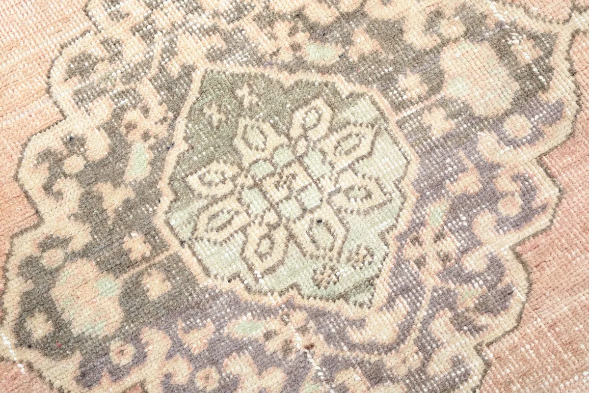 Macro detail of a gray and beige medallion, revealing the hand-knotted texture and slight color shifts