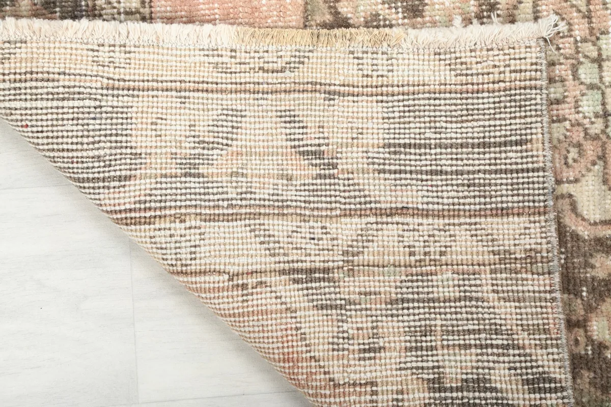 Close-up of the rug's cotton foundation and hand-knotted wool pile from the reverse side