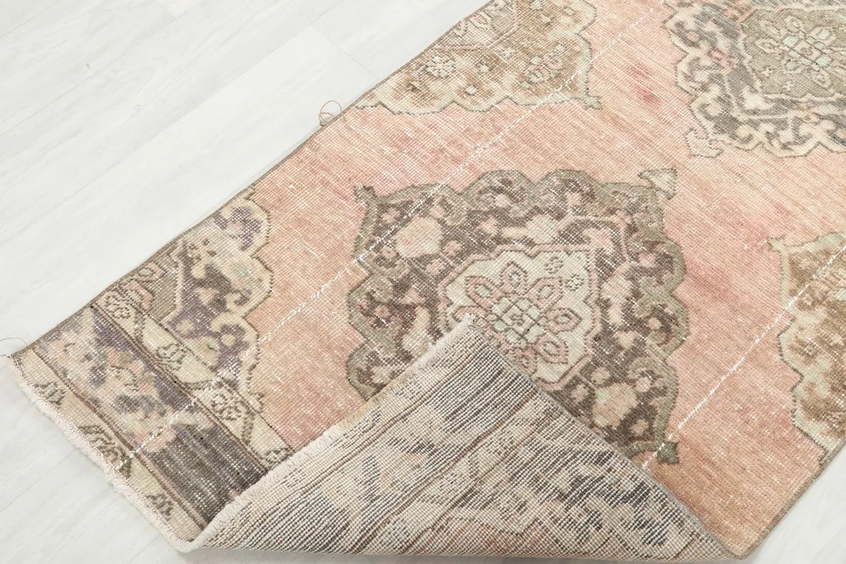 View of the rug folded back, showing the back of the rug and the intricate knotting