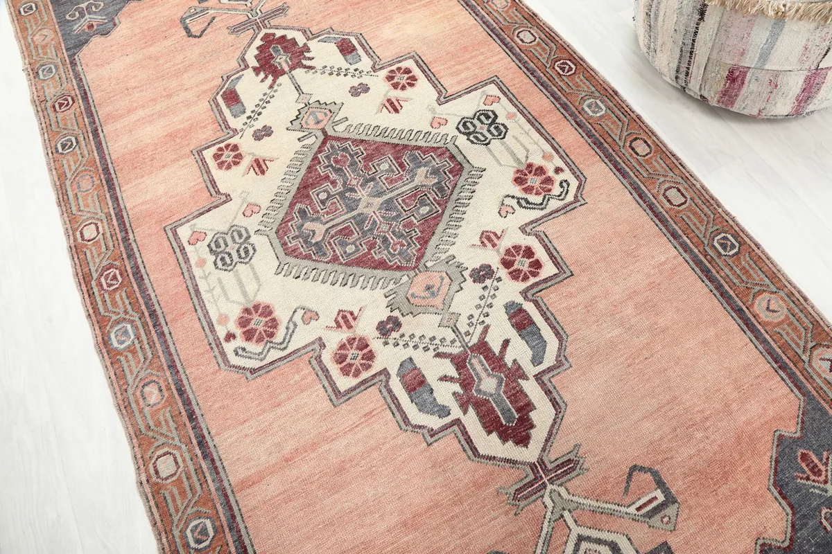 Angled view highlighting the central medallion and geometric details of the vintage orange rug