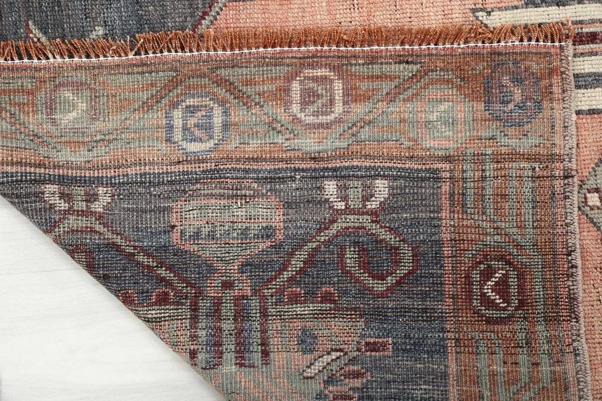 Close-up of the back of the hand-knotted orange rug, revealing the intricate weaving