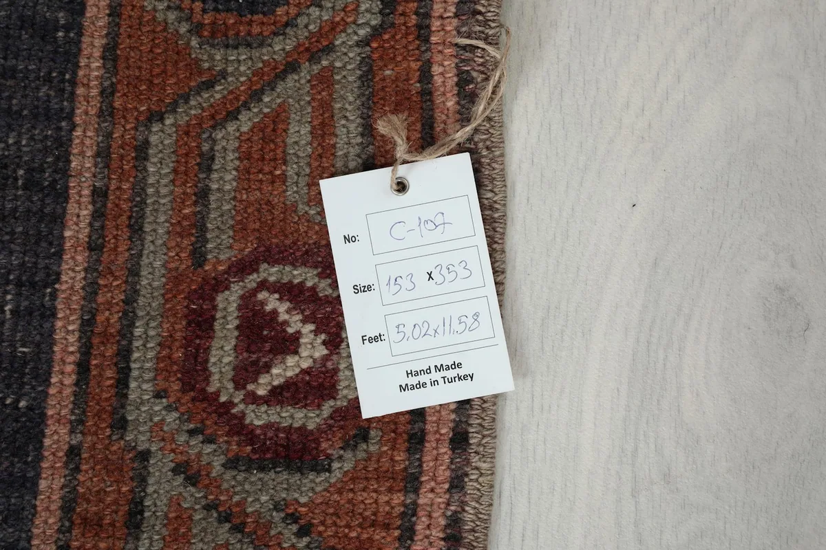 Close-up of the size tag attached to the rug, showing dimensions 153 x 353 cm and 5'0" x 11'7"