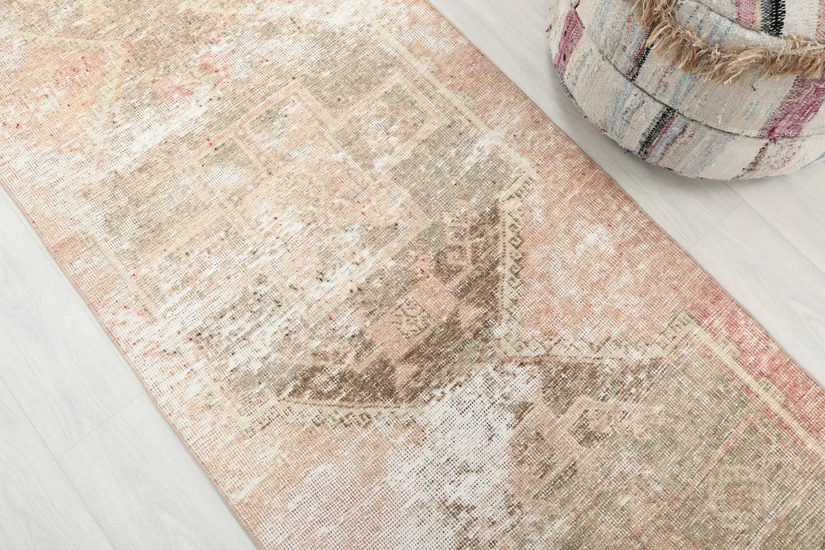 Detailed view of the faded geometric motifs and color variations on the runner rug