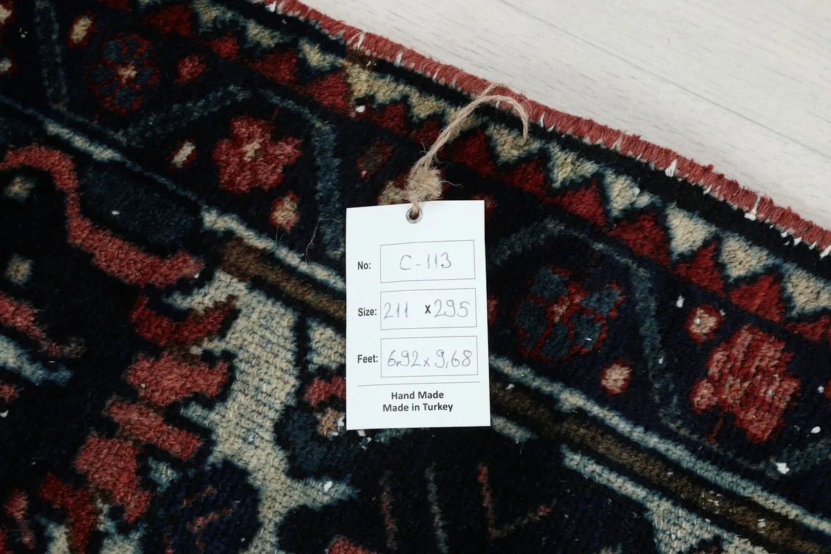 Close-up of the rug's edge with a product tag displaying size information in centimeters and feet.