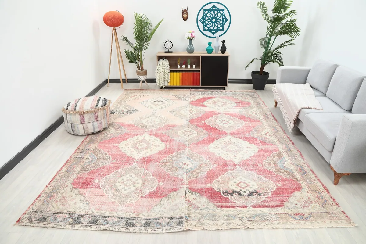 Large rose and red vintage rug in a modern living room setting with a gray sofa