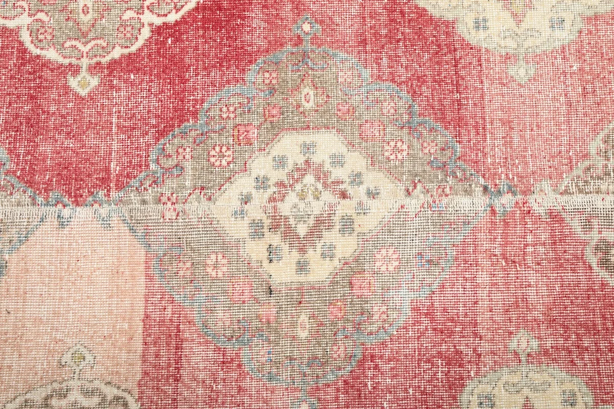 Close-up of a central medallion with beige and gray tones against the rose field