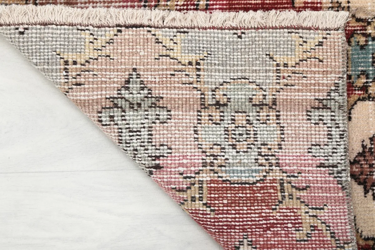 Close-up of the back of the rug, illustrating the tight knotting of the wool pile on a cotton foundation.