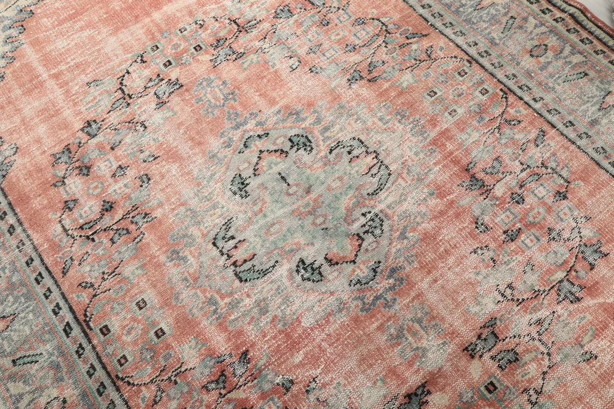 Close-up detail of the central medallion and floral motifs in rose, gray, and blue