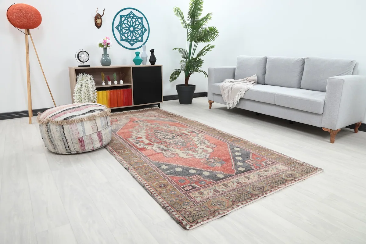 Angle view of the rust and brown area rug in a room, showing its placement next to a sofa and ottoman.
