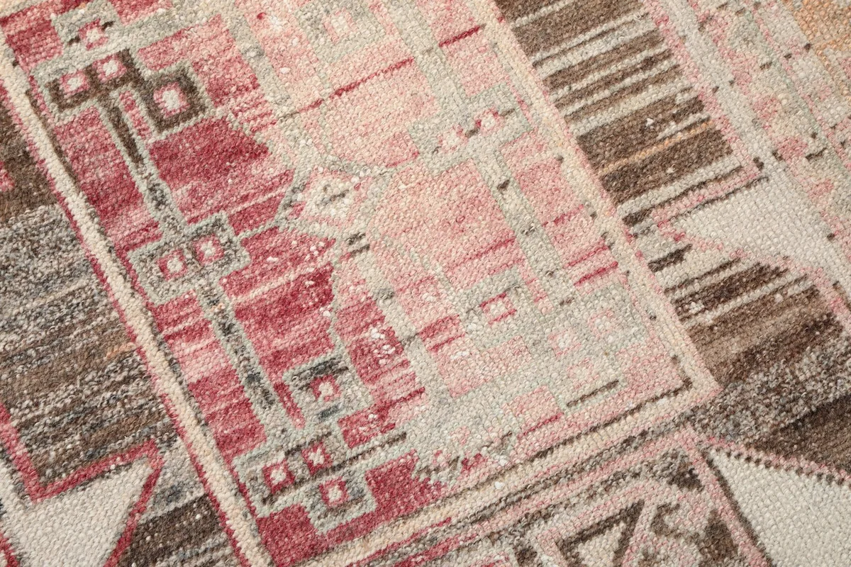 Macro shot of the rug's texture and color blend, with rose, beige, and gray threads