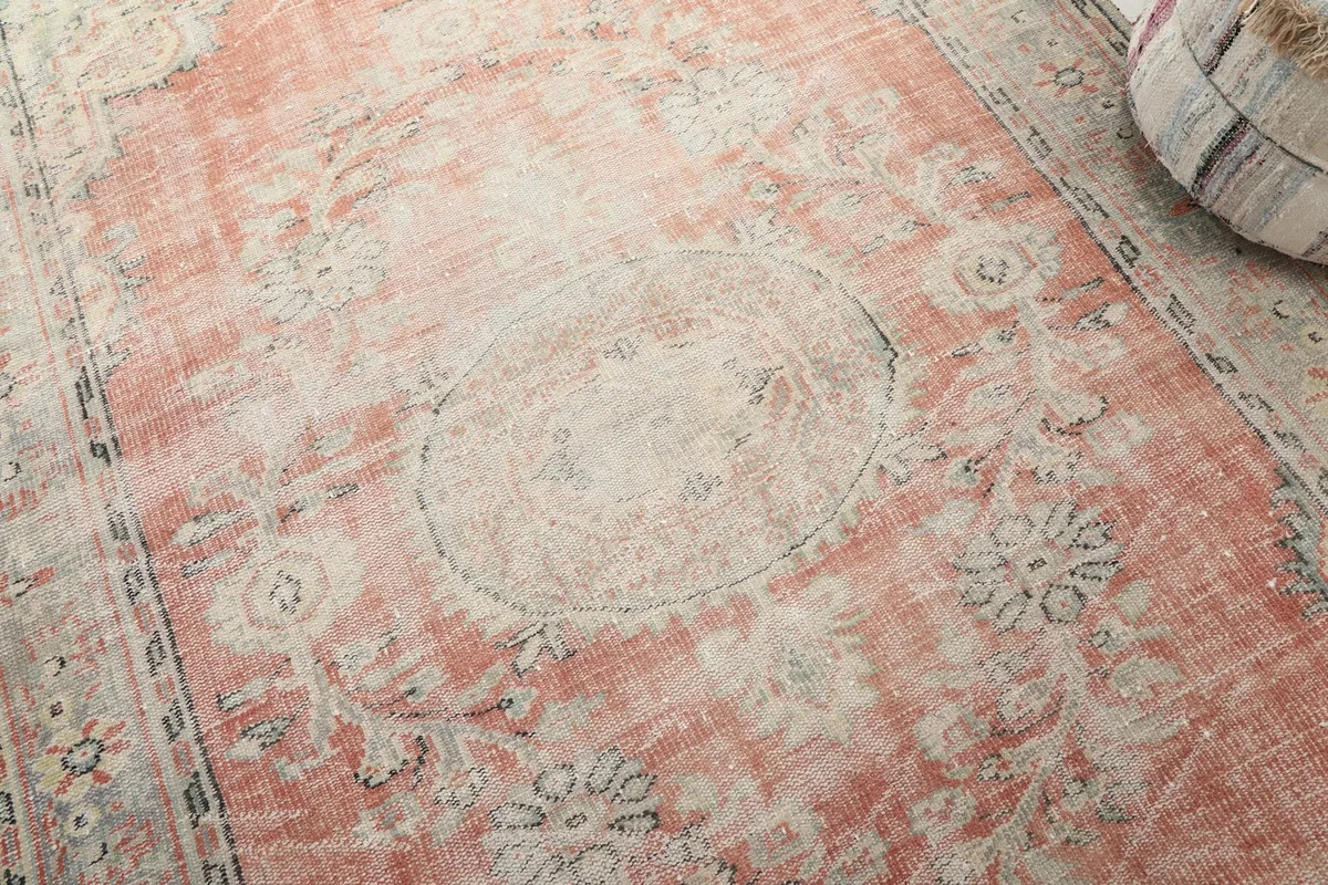 Close-up of the rug's central medallion and surrounding floral motifs, revealing the distressed texture.