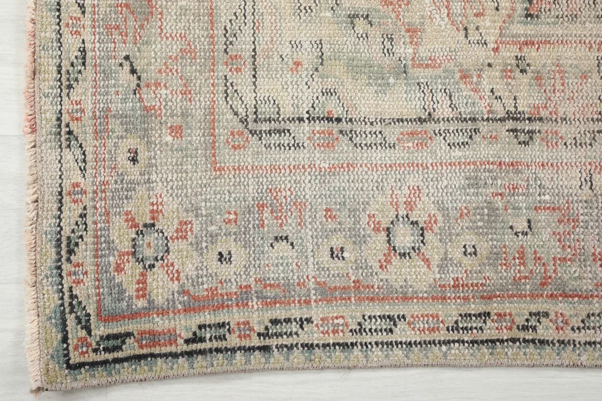 Close-up of the rug's border, featuring geometric patterns in beige, gray, and black tones.