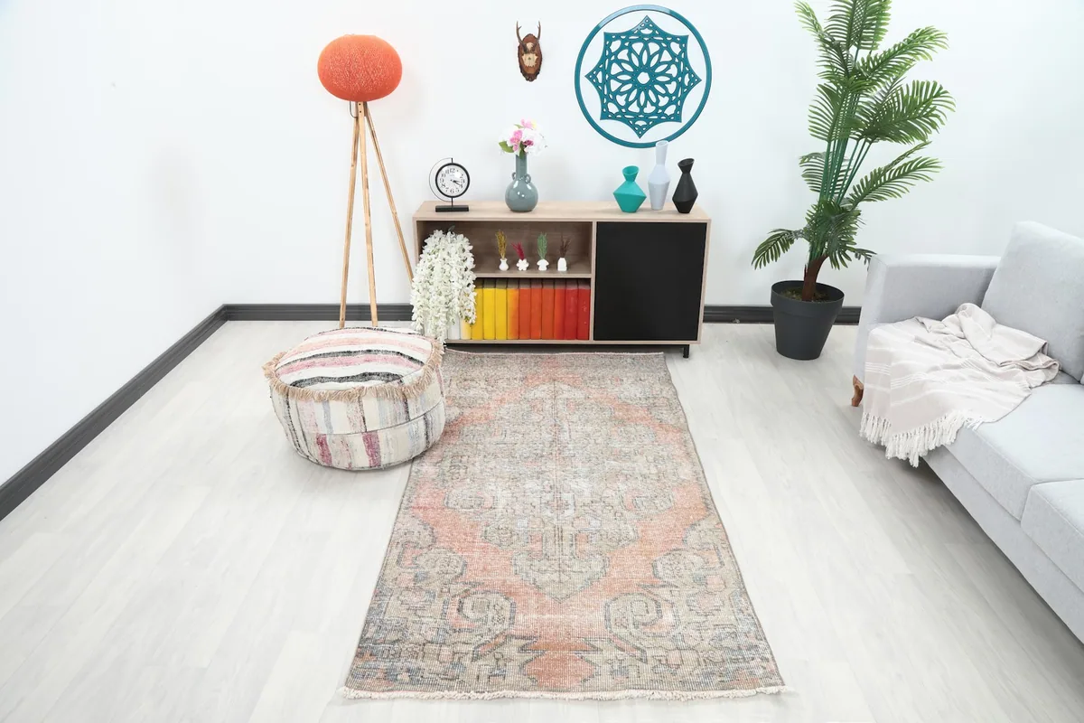 Rust and beige vintage rug in a modern living room setting with a gray couch and white walls.