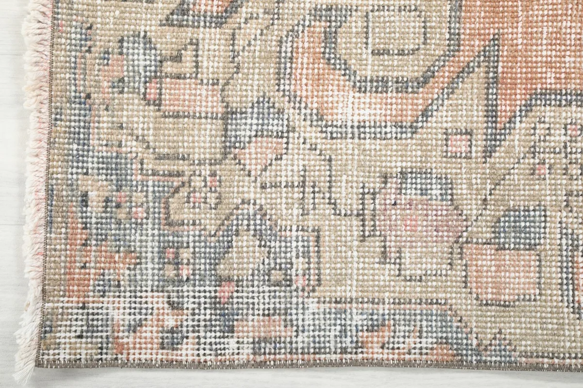 Close-up of the rug's border and fringe, highlighting the intricate geometric knotting.