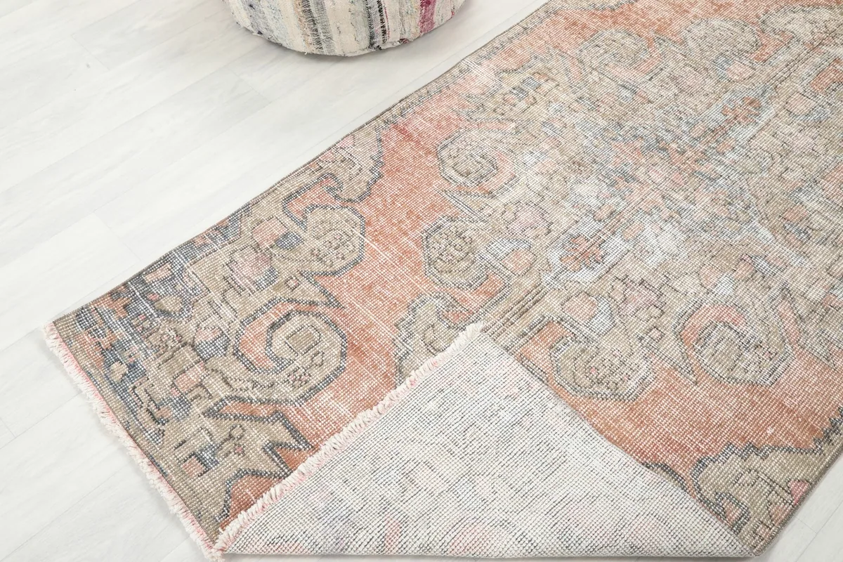 Corner of the rug folded back, revealing the wool pile and cotton foundation.