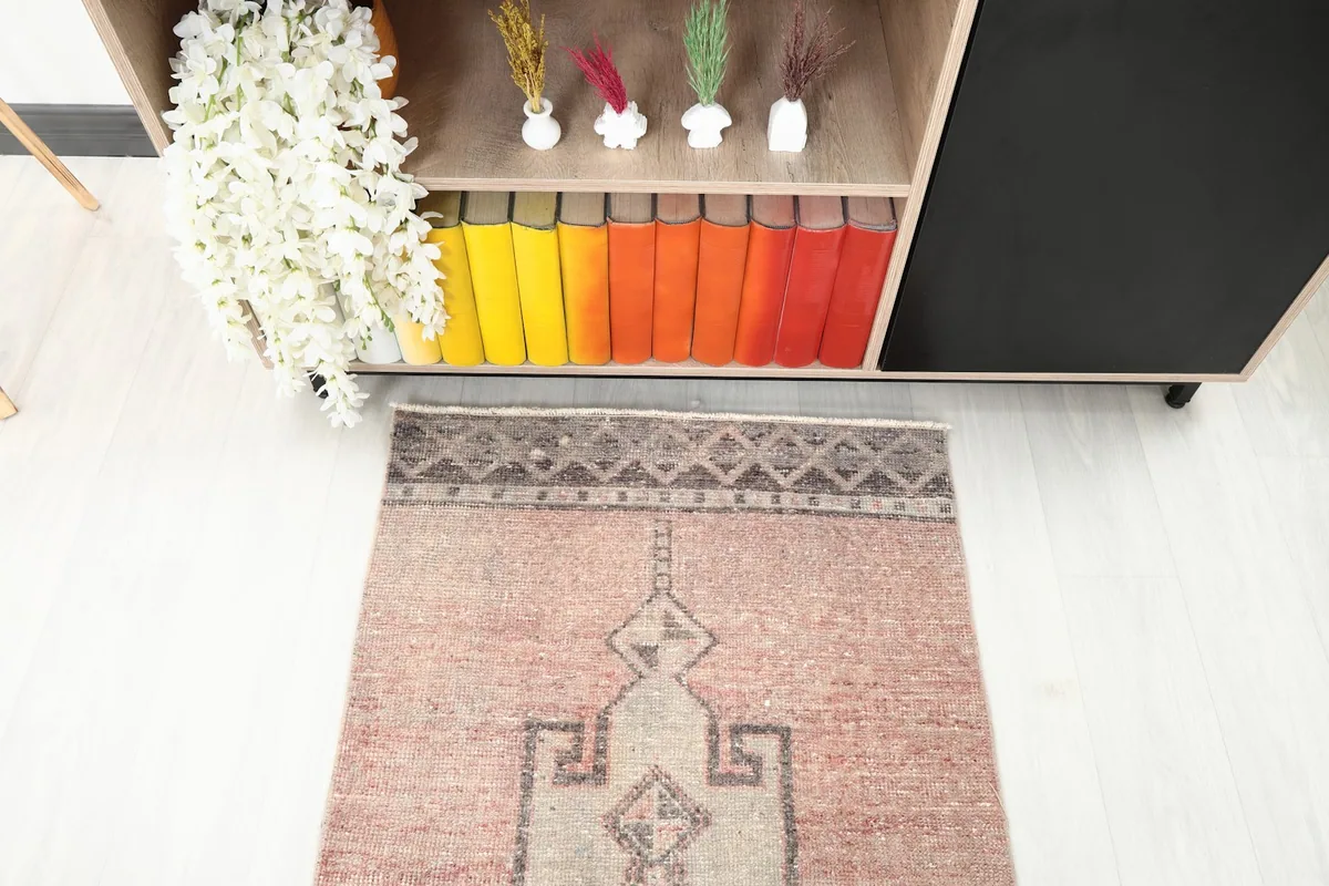 Overhead detail shot of one end of the rug, showing the geometric border and central motifs.