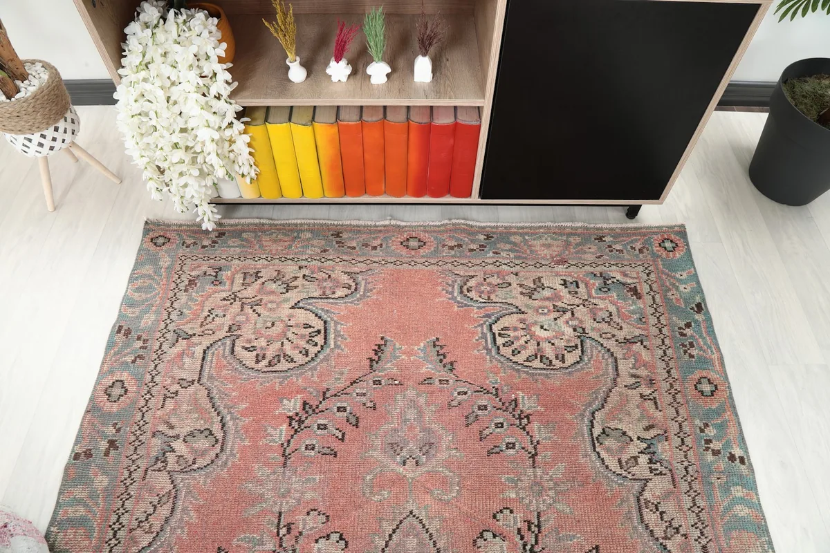 Angled view of the vintage rose and blue rug's upper section in a room