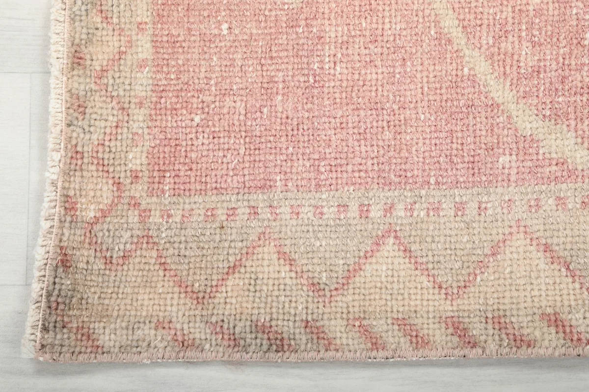 Detail of the distinct beige border with its geometric motif, showcasing the craftsmanship and vintage patina.