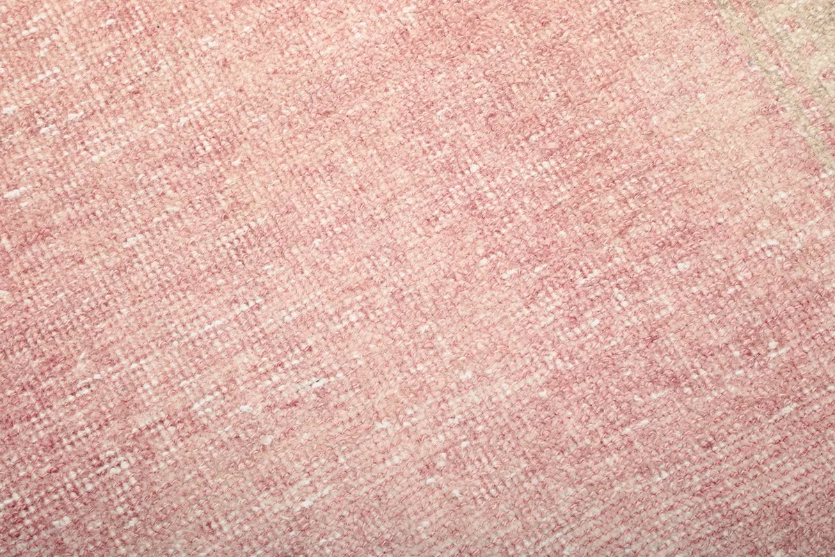 Close-up of the low wool pile, showing the texture and subtle color variations within the rose pink field.