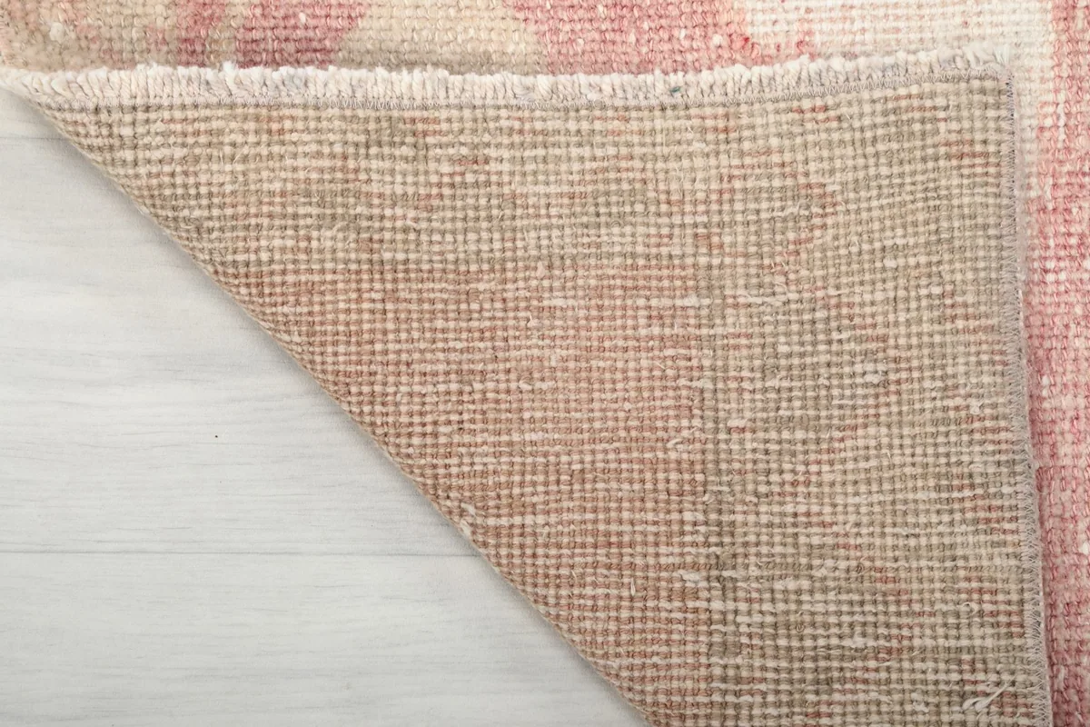 Close-up of the back of the runner rug, showing the tight hand-knotted cotton foundation and wool knots.
