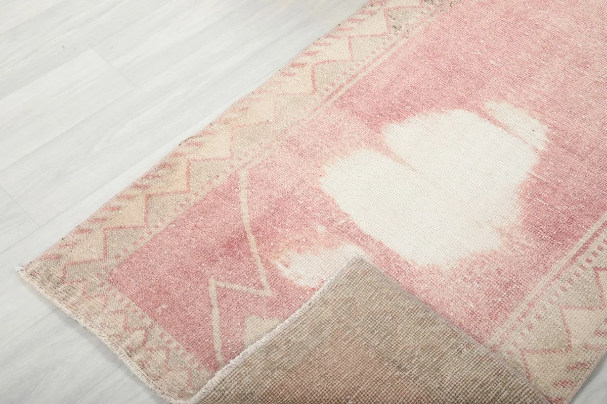 Corner of the runner rug folded back, revealing the reverse side and the hand-knotted cotton foundation.