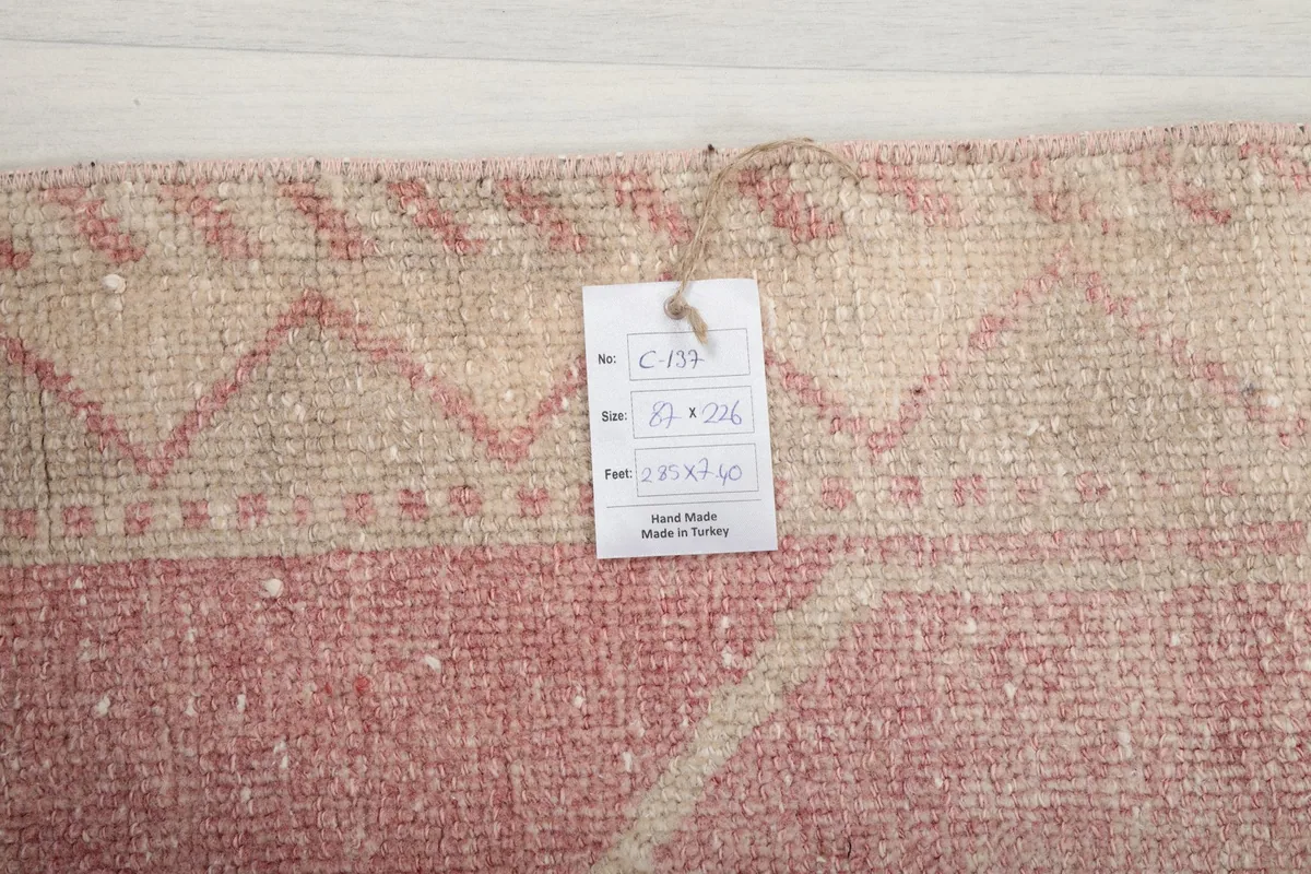Corner of the rug with a product tag displaying size in cm and inches, confirming its origin and hand-knotted nature.
