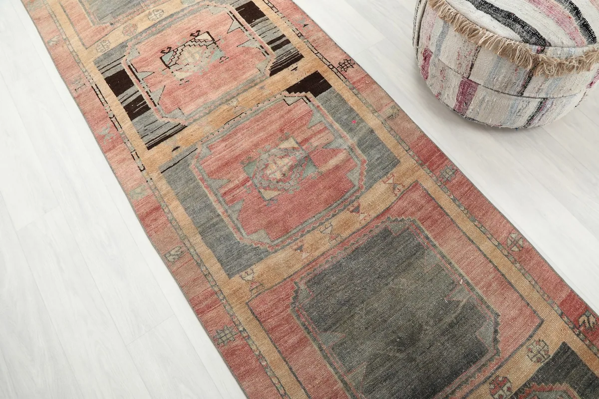 Angled view down the length of the runner rug, showing the sequence of rose and gray patterns