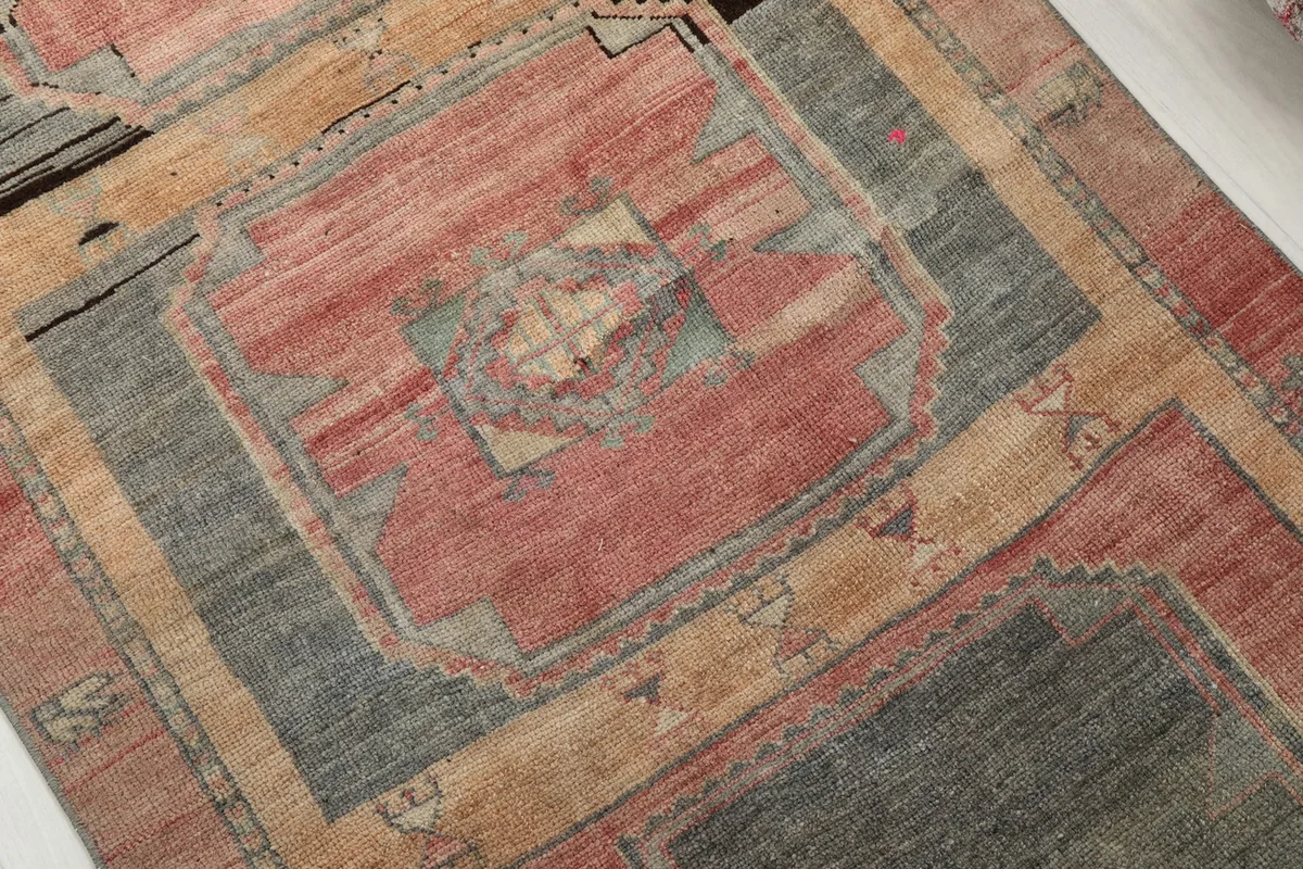 Close-up detail of the hand-knotted wool pile and color variations in a rose and gray medallion