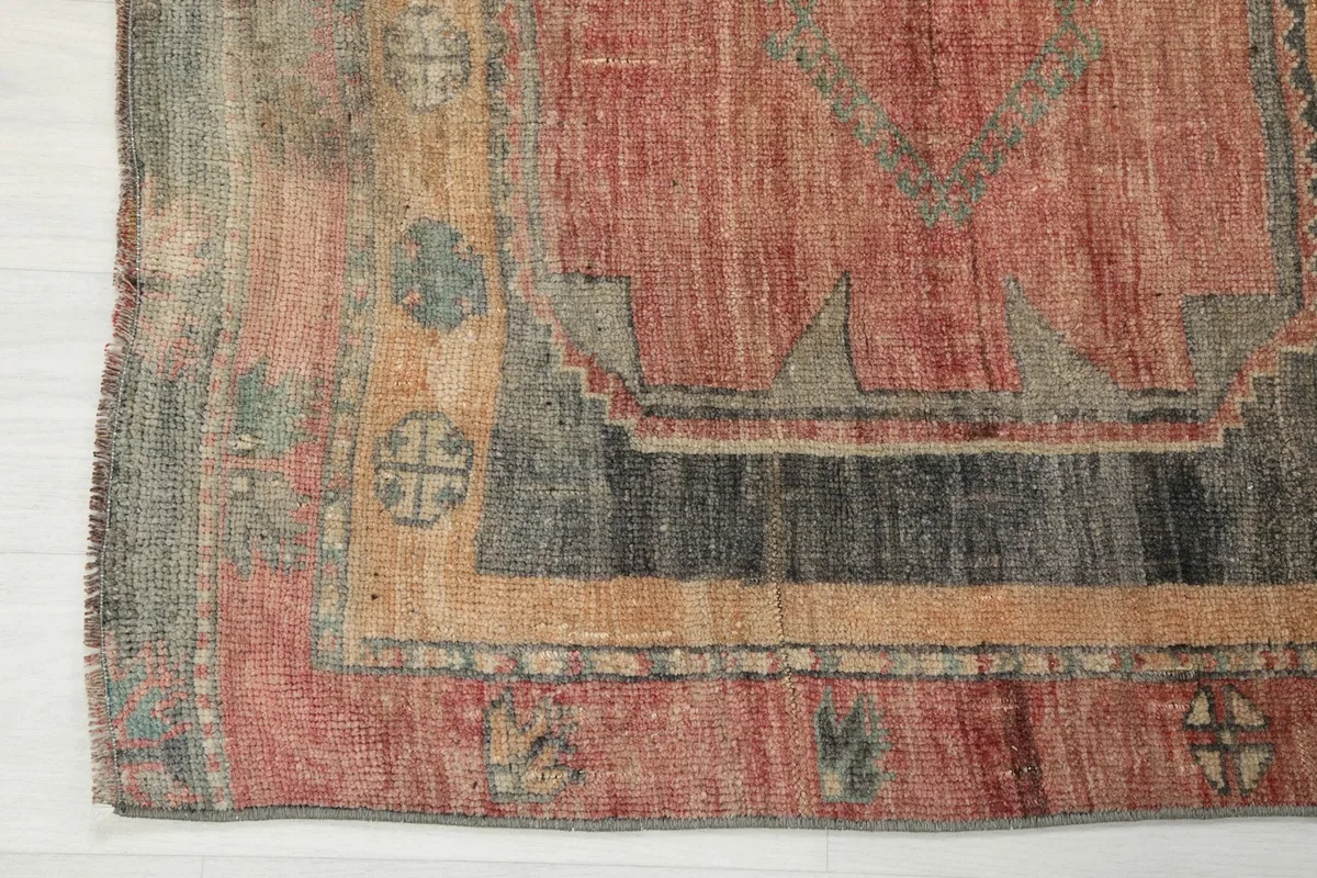 Detail of the rug's border with tribal motifs and the edge showing natural wear
