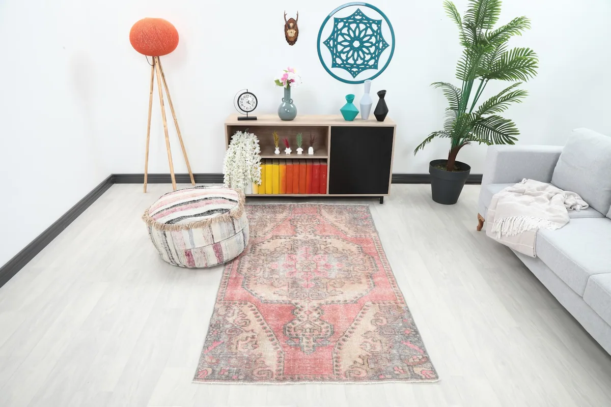 Vintage rose and beige rug displayed in a bright living room setup with a gray sofa and plant.