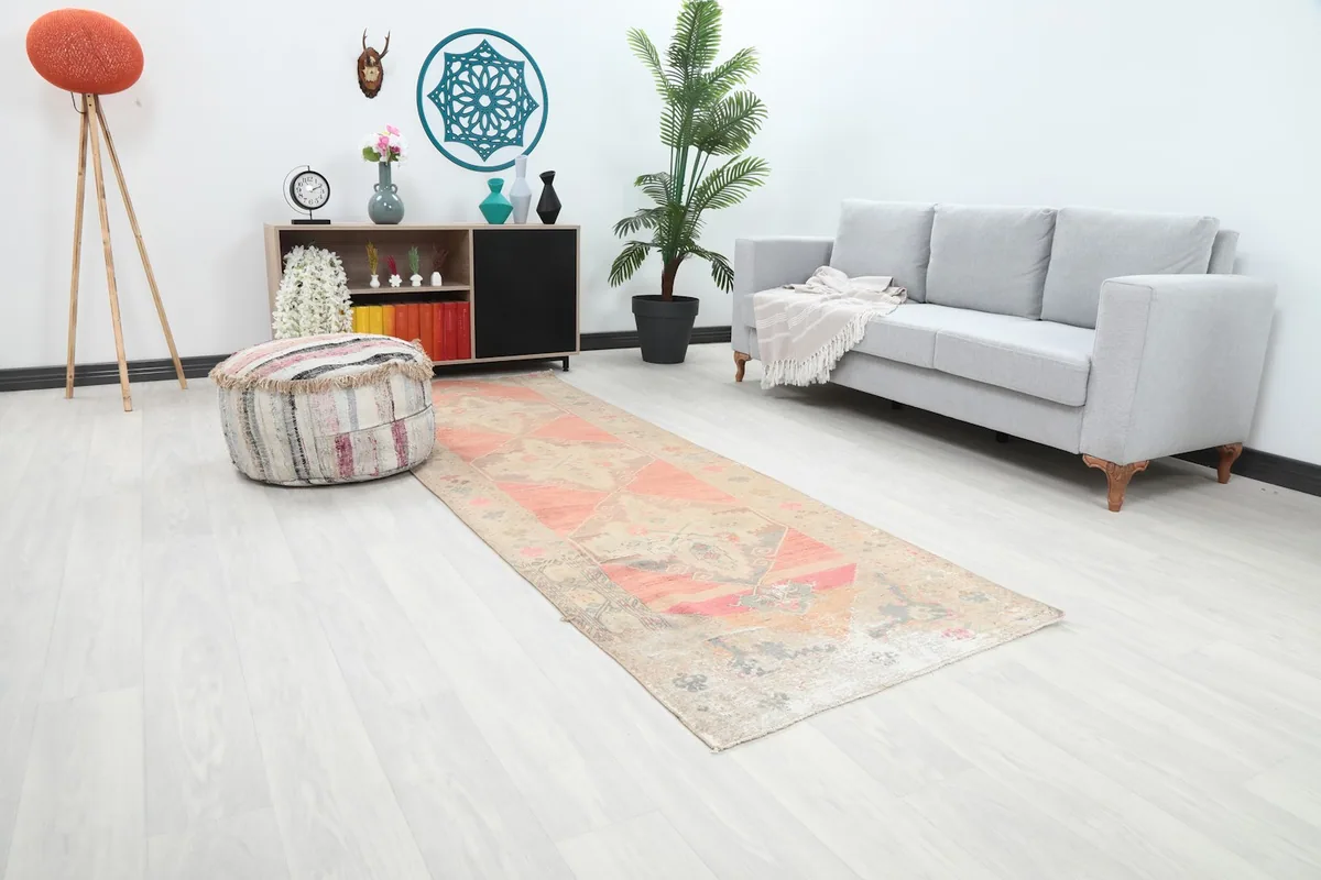 Angle view of the rose and beige geometric runner rug in a bright room setting