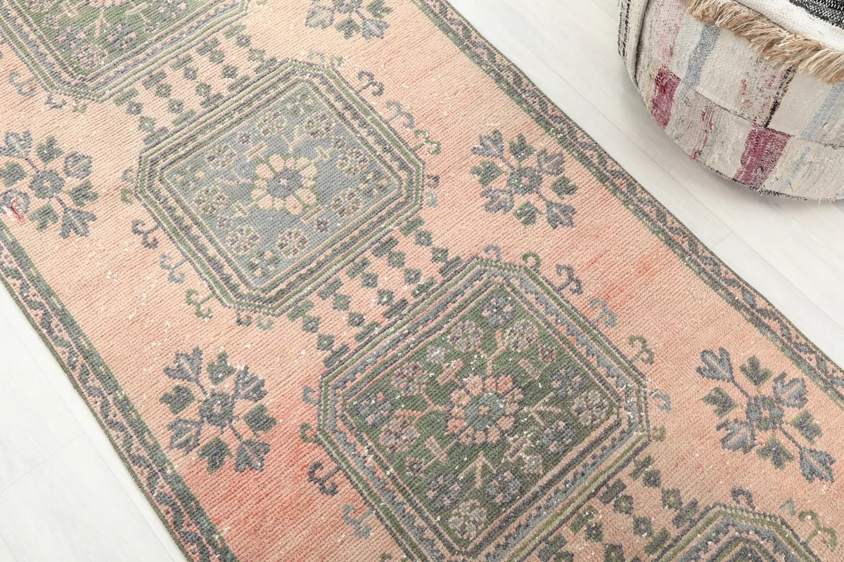 Detailed view of the rose field and gray and green geometric motifs on the vintage runner.