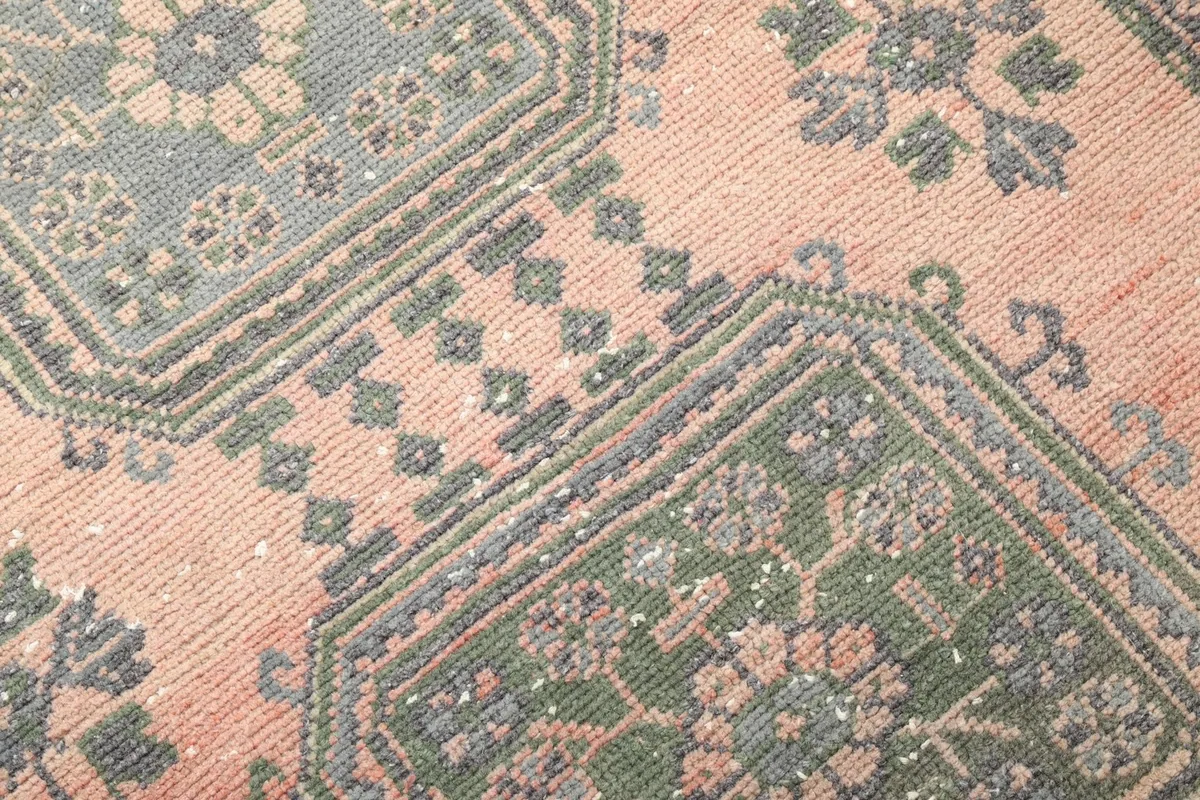 Close-up of the hand-knotted wool pile and intricate geometric patterns in gray and green.
