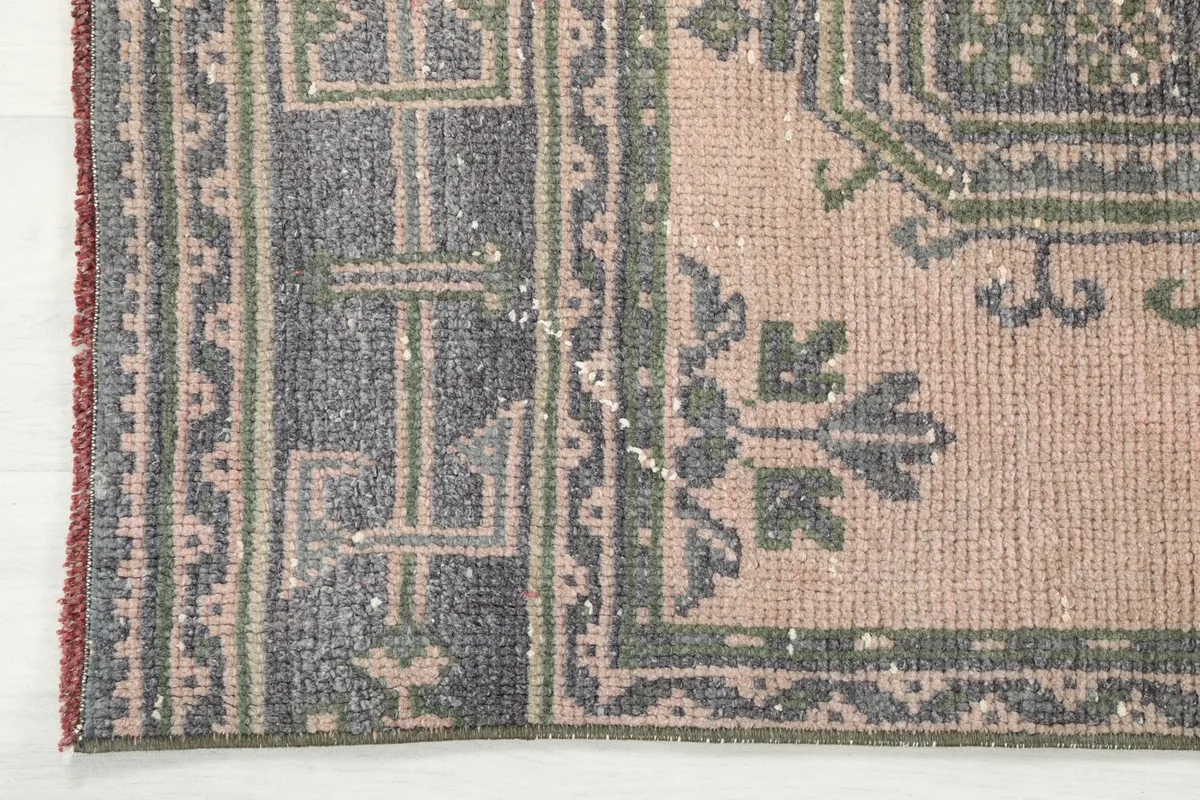 Corner detail of the runner rug, showing the gray border design and rose field.