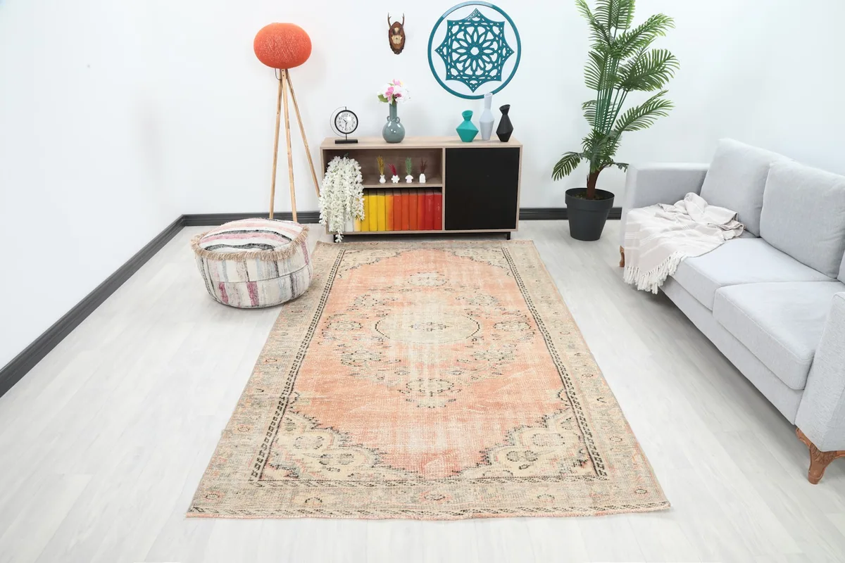 Orange floral medallion rug in a modern living room setting with a gray sofa and wooden cabinet