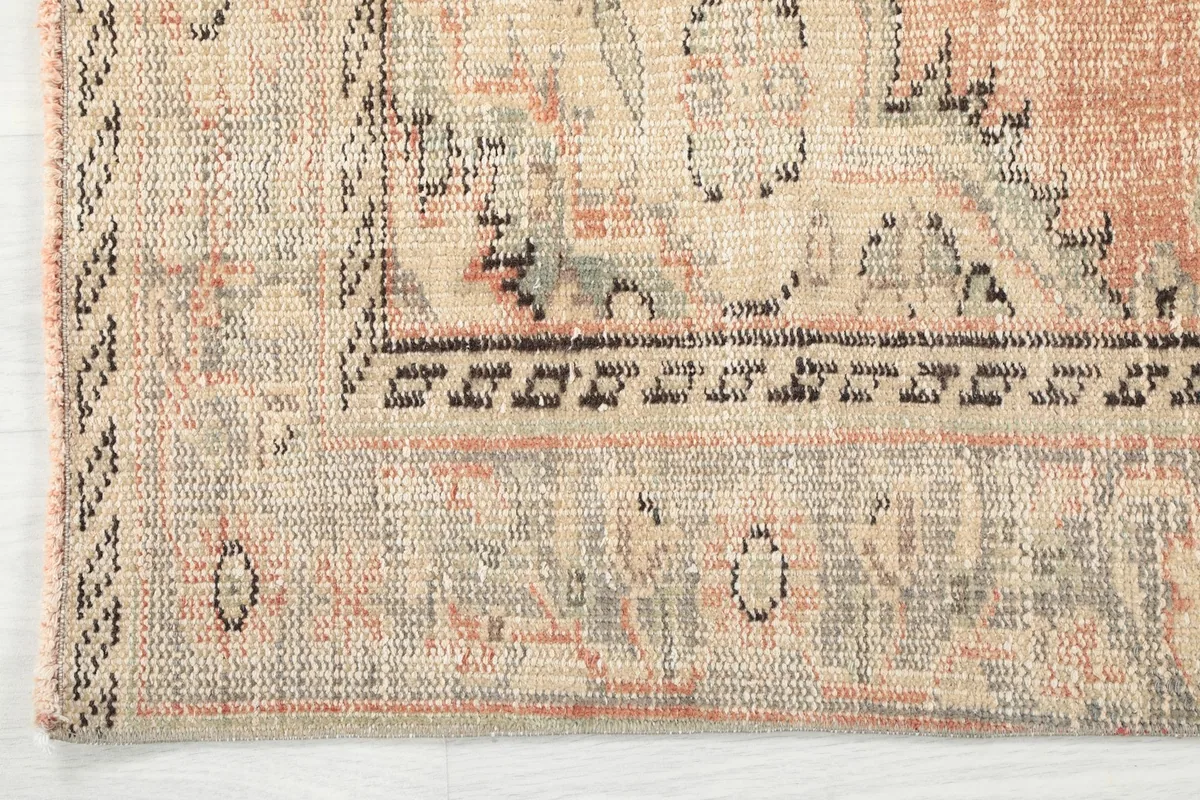 Close-up of the rug's border, showcasing the geometric and floral patterns in beige and charcoal
