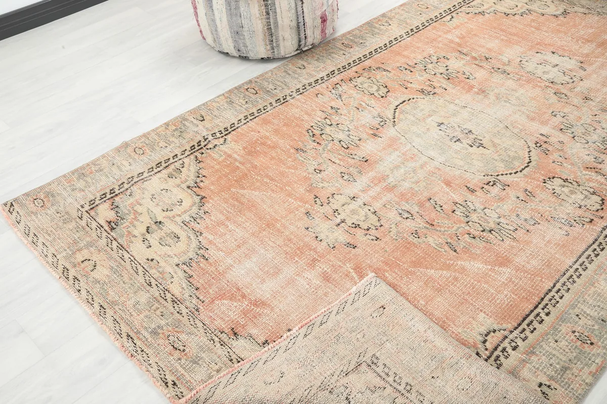View of the rug folded over, showing the texture and the faded orange and beige colors