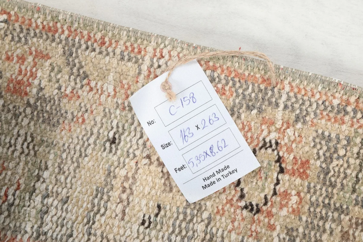 Close-up of the rug's reverse side with a tag showing its size in centimeters and feet, and origin