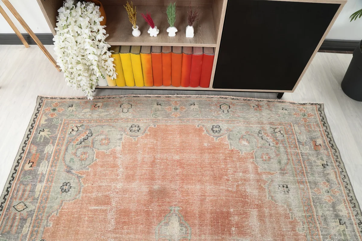 Close-up angle showing the top portion of the rust and gray rug in a room
