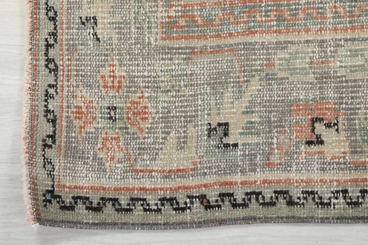 Detail of the rug's outer border, showing intricate geometric motifs and edge finishing