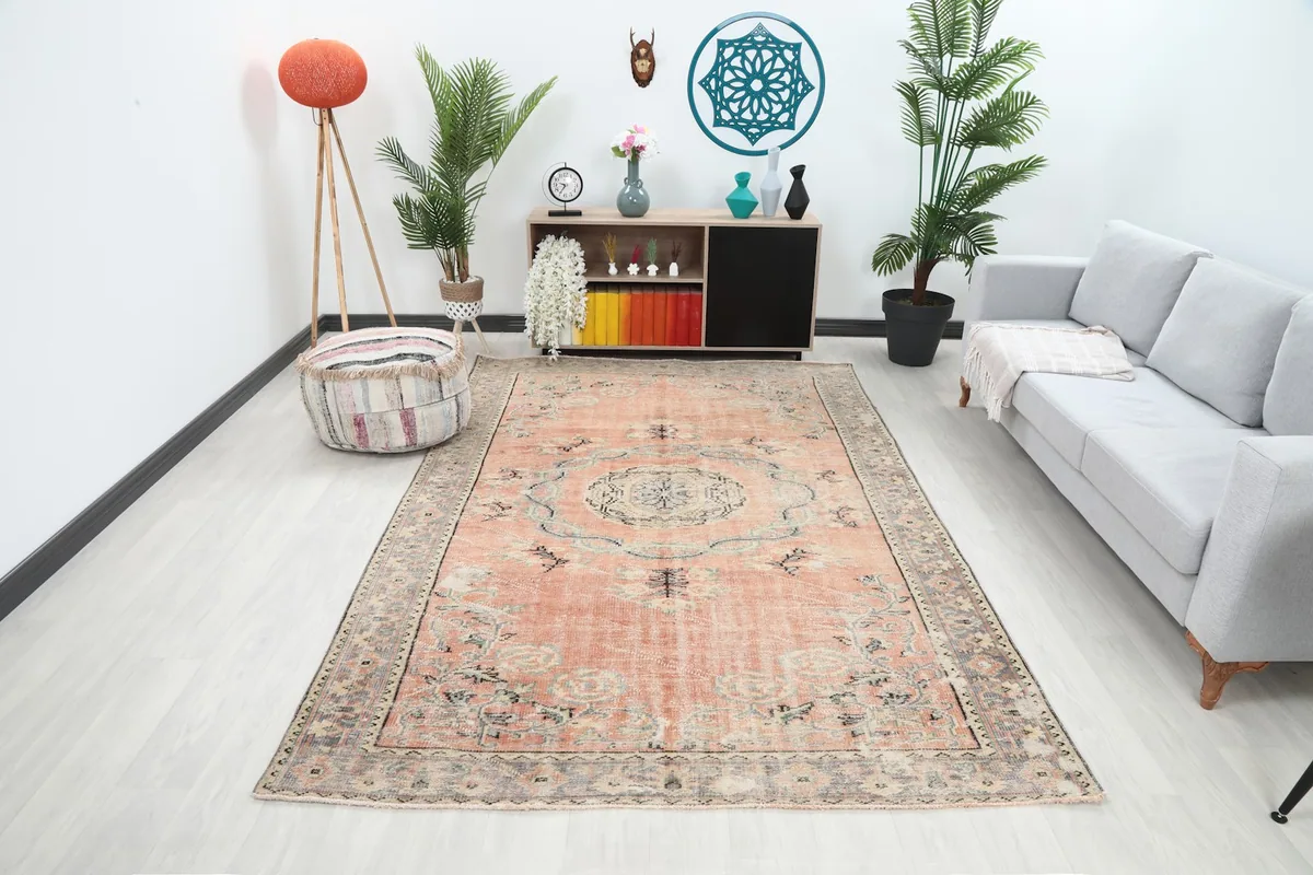 Vintage rose Anatolian rug displayed in a modern living room setting with a gray sofa and plants