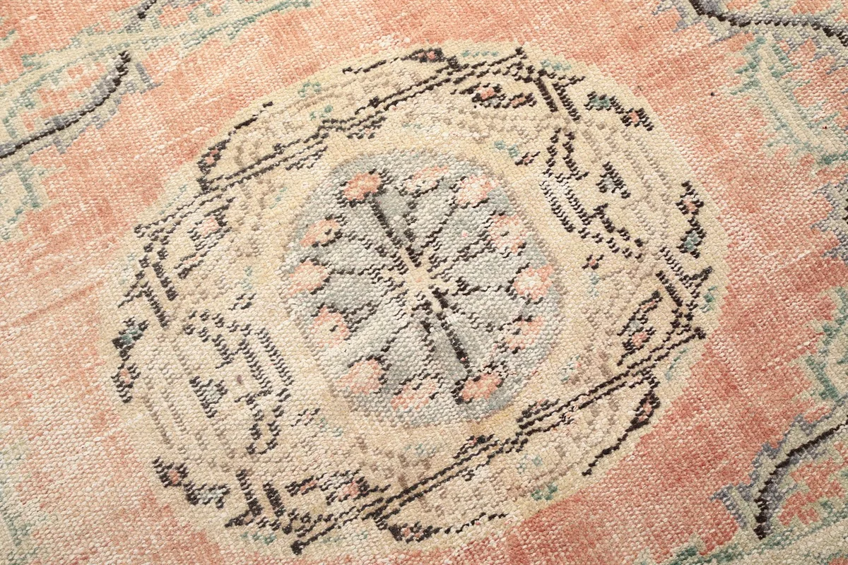 Detailed view of the intricate patterns within the central medallion of the rose Anatolian rug